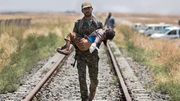 A Kurdish People's Protection Units (YPG) fighter carries a boy injured by what they said was a mine after they fled Maskana town in the Aleppo countryside and make their way towards the Turkish border in Tel Abyad. (File photo: Reuters)