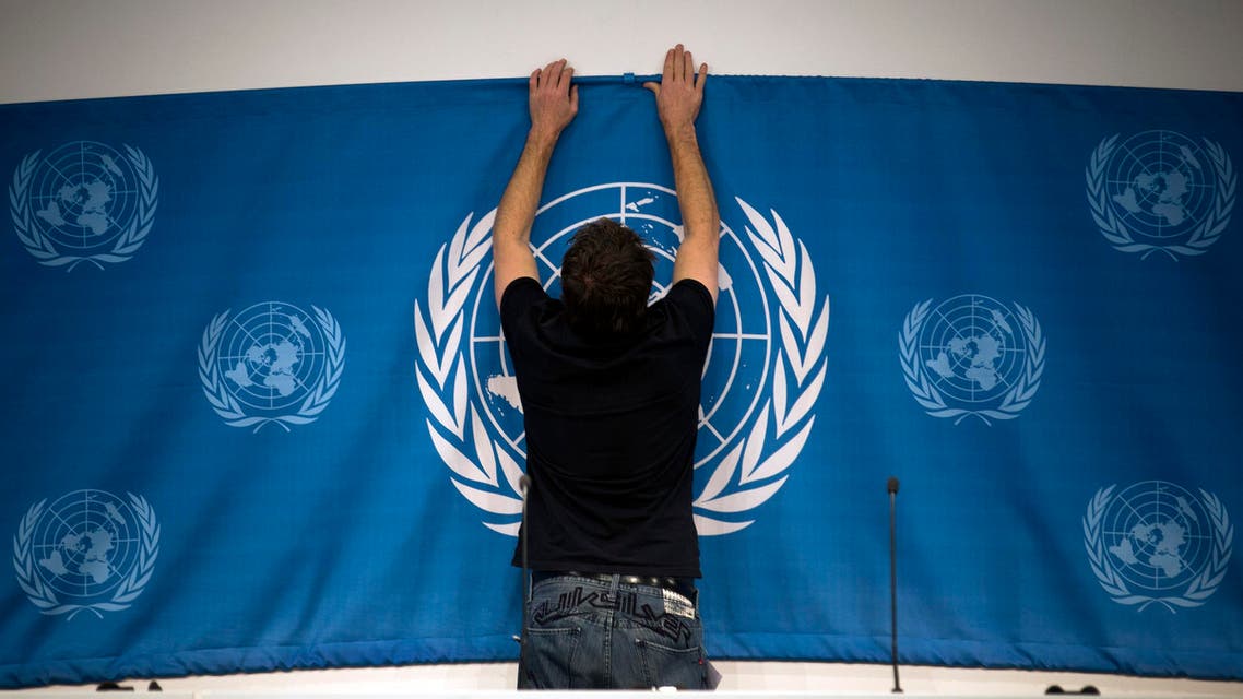 A worker sets up a United Nations banner at the media center in preparations for the start of this week's Syria peace talks in Montreux and Geneva, in Montreux, Switzerland, Tuesday, Jan. 21, 2014. Russia and Iran on Tuesday criticized the U.N. chief’s decision to withdraw Tehran’s invitation to join the peace conference on Syria, as diplomats said a new report on Syrian regime atrocities underscored the urgent need to try to end the country’s brutal civil war. (AP Photo/Anja Niedringhaus)