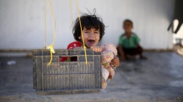 A Syrian refugee child reacts while sitting in a swing in Al Zaatari refugee camp, in the Jordanian city of Mafraq. (Reuters)