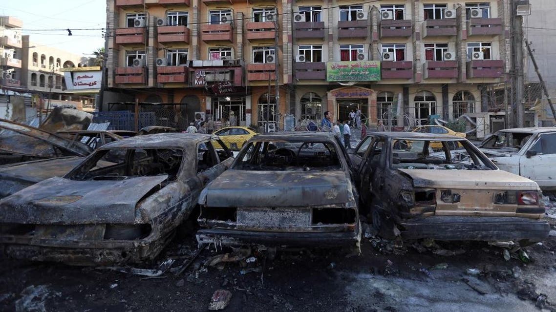Civilians inspect the aftermath of a car bombing near a restaurant in a commercial area of central Baghdad, Iraq, Tuesday, Sept. 29, 2015. Iraqi officials say a car bomb exploded around midnight Monday in central Baghdad killing and wounding civilians. (AP Photo/Hadi Mizban)