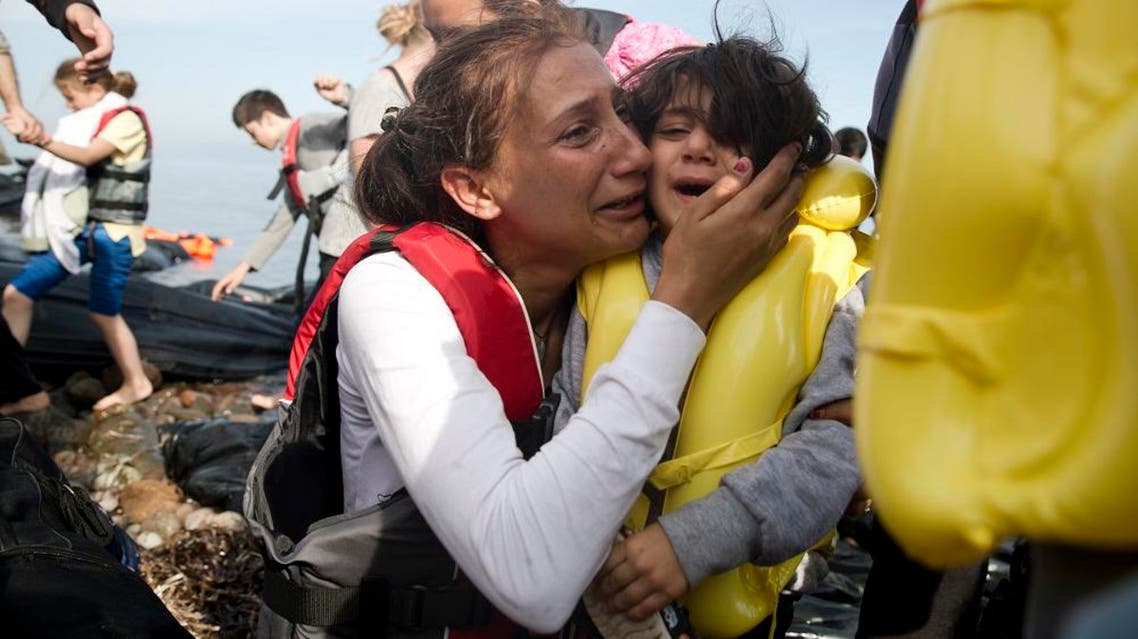 A Syrian woman and her child react after they arrived with others from Turkey on the shores of the Greek island of Lesbos, on a inflatable dinghy, Sunday Sept. 27, 2015. More than 260,000 asylum-seekers have arrived in Greece so far this year, most reaching the country's eastern islands on flimsy rafts or boats from the nearby Turkish coast.(AP Photo/Petros Giannakouris)