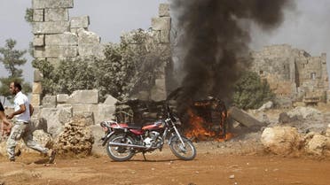 A man runs past a burning military vehicle at a base controlled by rebel fighters from the Ahrar al-Sham Movement in the southern countryside of Idlib. (Reuters)