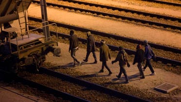 Migrants walk along the train tracks after crossing a fence as they attempt to access the Channel Tunnel in Calais, Friday, Aug. 7, 2015. 
