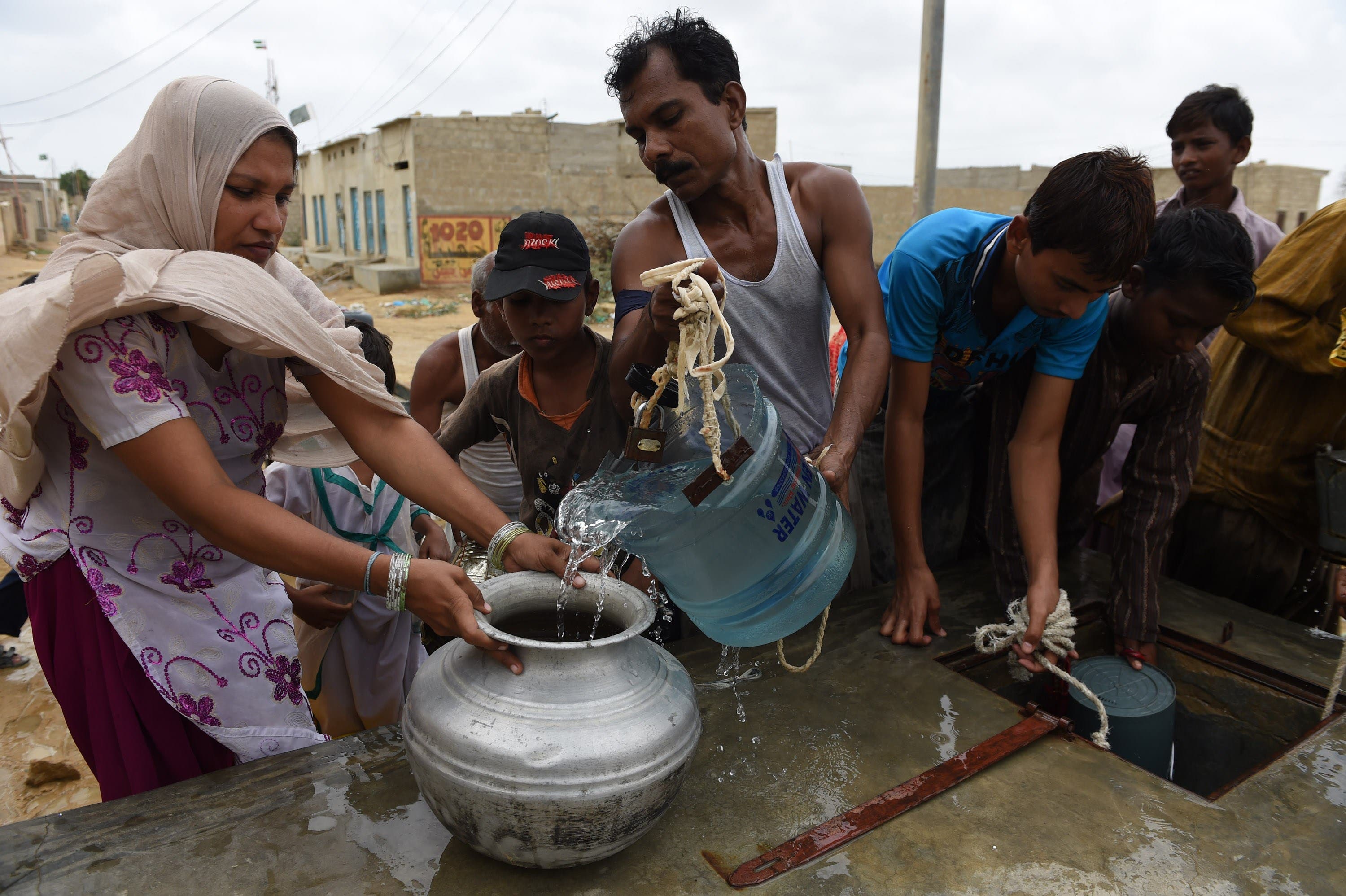 In this photograph taken on August 22, 2015, Pakistani residents fill containers with water provided by the government in a slum area of Karachi.