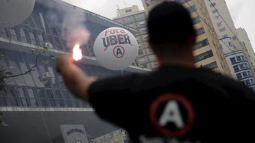  A taxi driver holds a flare in front of a balloon that reads ‘Out Uber’ during a protest against the online car-sharing service in Sao Paulo in September 2015. (Reuters)