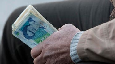 An Iranian street money exchanger holds Iranian banknotes with a portrait of late revolutionary founder Ayatollah Khomeini, pictured in Jan. 2012. (File photo: AP)