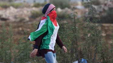 Masked Palestinian girl, draped in a Palestinian flag, walks during clashes with Israeli troops near the Jewish settlement of Bet El. (File photo: Reuters)