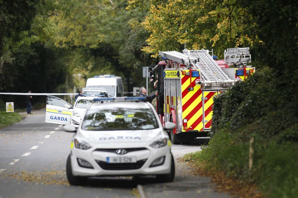 An Irish police officer talks with a fireman at the police cordon outside the halting site in the south Dublin suburb of Carrickmines, Ireland, on October 10, 2015 where a fire killed at least nine people. Nine people, including a baby and older children, have died in a fire at a site in Dublin housing members of the traveller community, police said October 10. A number of other people were taken to hospital after inhaling smoke at the site housing caravans and prefabricated buildings. AFP PHOTO