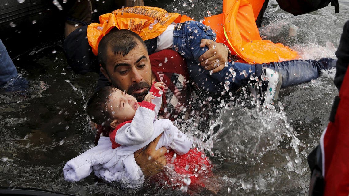 A Syrian refugee holds onto his children as he struggles to walk off a dinghy on the Greek island of Lesbos, after crossing a part of the Aegean Sea from Turkey to Lesbos September 24, 2015. (AP)