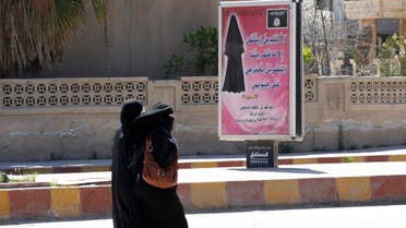 Veiled women walk past a billboard that carries a verse from Koran urging women to wear a hijab in the northern province of Raqqa. (File photo: Reuters)