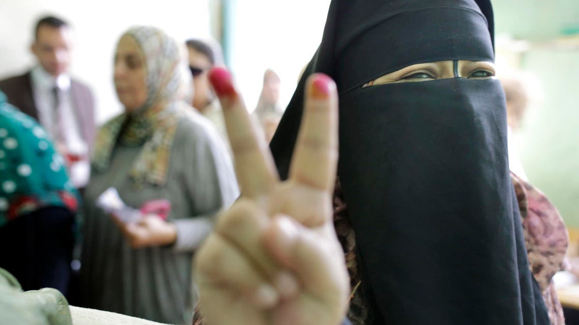 An Egyptian voter gestures with her inked fingers after casting her ballot at polling station during the first round of parliamentary elections, in Giza, Cairo, Egypt, Sunday, Oct. 18, 2015. (AP)