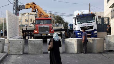 Palestinians watch a wall being built between Palestinian and Jewish neighborhoods in Jerusalem Sunday, Oct. 18, 2015. Palestinians in Jerusalem, more than one-third of the city's population, have awoken to a new reality: Israeli troops are encircling Arab neighborhoods, blocking roads with cement cubes the size of washing machines and ordering some of those leaving on foot to bare their torsos to prove they not carrying knives. (AP Photo/Mahmoud Illean)