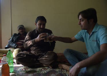 In this photograph taken on September 27, 2015, local resident Rehmat Ali (R) and his cousin toast each other as they prepare to drink home brewed wine in the remote village of Sher Qilla in Punyal valley in northern Pakistan.