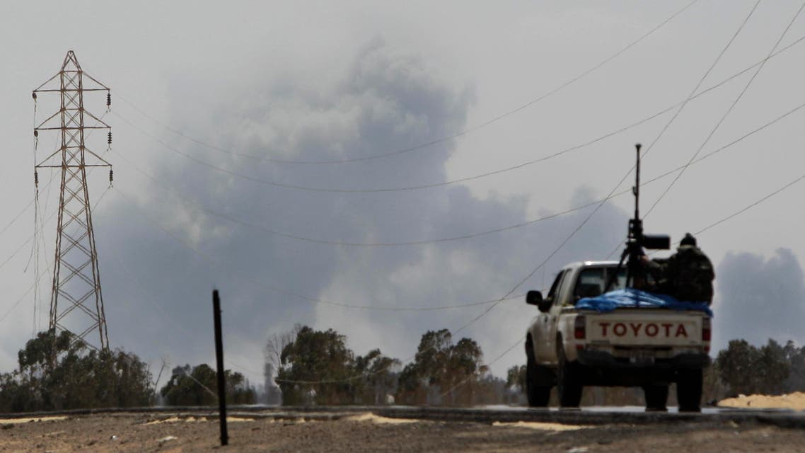A Libyan rebel vehicle drives toward the town as a large explosion, possibly a NATO airstrike, rises above it in Ajdabiya, Libya Saturday, April 9, 2011. NATO officials did not immediately confirm the attack but the British military said its warplanes hit seven tanks around Ajdabiya and the rebel-held city of Misrata in western Libya on Friday as part of the NATO-led mission. (AP Photo/Ben Curtis)