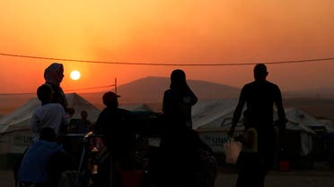Iraqi refugees, who fled from the violence in Mosul, use containers to collect water during sunset inside the Khazer refugee camp on the outskirts of Arbil, in Iraq's Kurdistan region, June 27, 2014. G