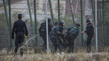 Sub-Saharan migrants are sent back to the Moroccan side escorted by Spanish Guardia Civil officers after climbing a metallic fence that divides Morocco and the Spanish enclave of Melilla. (AP)