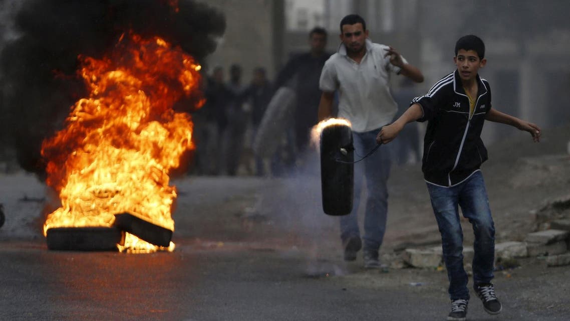 Palestinian moves a burning tyre during clashes with Israeli troops in the West Bank village of Si'eer north of the West Bank city of Hebron. (Reuters)