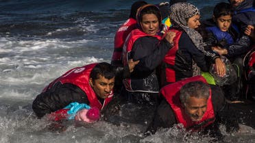 A group of Afghan migrants, including a small child carried through the water by man at left, disembark safely from their frail boat in bad weather on the Greek island of Lesbos after crossing the Aegean see from Turkey, Wednesday, Oct. 28, 2015.