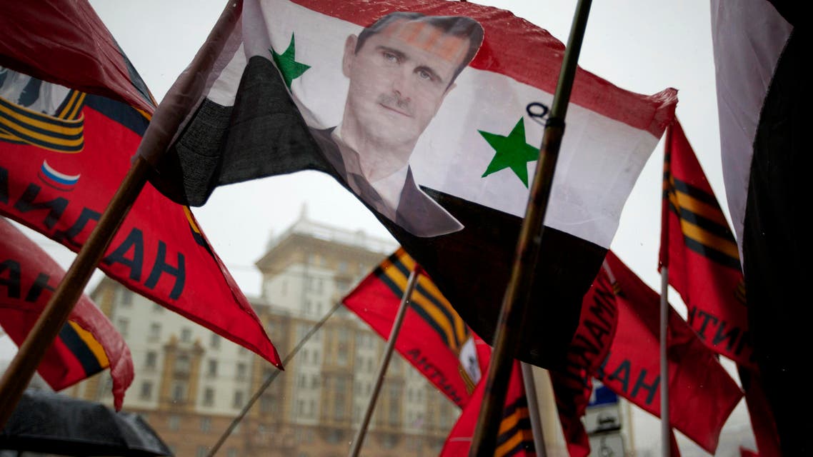 Pro-Kremlin youths hold a Syrian flag bearing a portrait of Syrian President Bashar al-Assad during a picket in protest against American policy in front of the U.S. Embassy in Moscow, Russia, Friday, April 3, 2015. (AP)