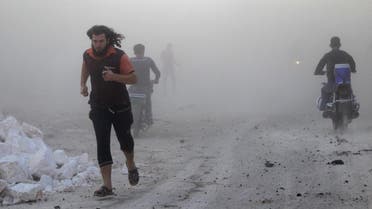 Residents run though dust in a site damaged by what activists said were airstrikes carried out by the Russian air force in the rebel-controlled area of Maaret al-Numan town in Idlib province. (File: Reuters)