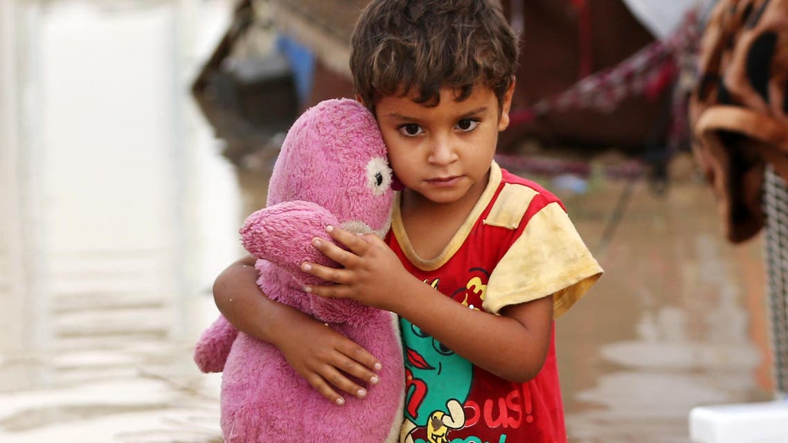 Omar Abdullah, 5, holds a stuffed animal outside his tent submerged in rainwater at a camp for displaced persons in Youssifiyah, 12 miles (20 kilometers) south of Baghdad, Iraq, Thursday, Oct. 29, 2015