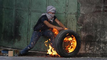 A young Palestinian protester pushes a burning tyre during clashes with Israeli troops in the West Bank city of Hebron October 31, 2015. Israeli security forces shot and killed a Palestinian who ran at them with a knife in the occupied West Bank on Saturday, police said, as a month-long wave of violence showed no signs of abating. REUTERS/Ammar Awad
