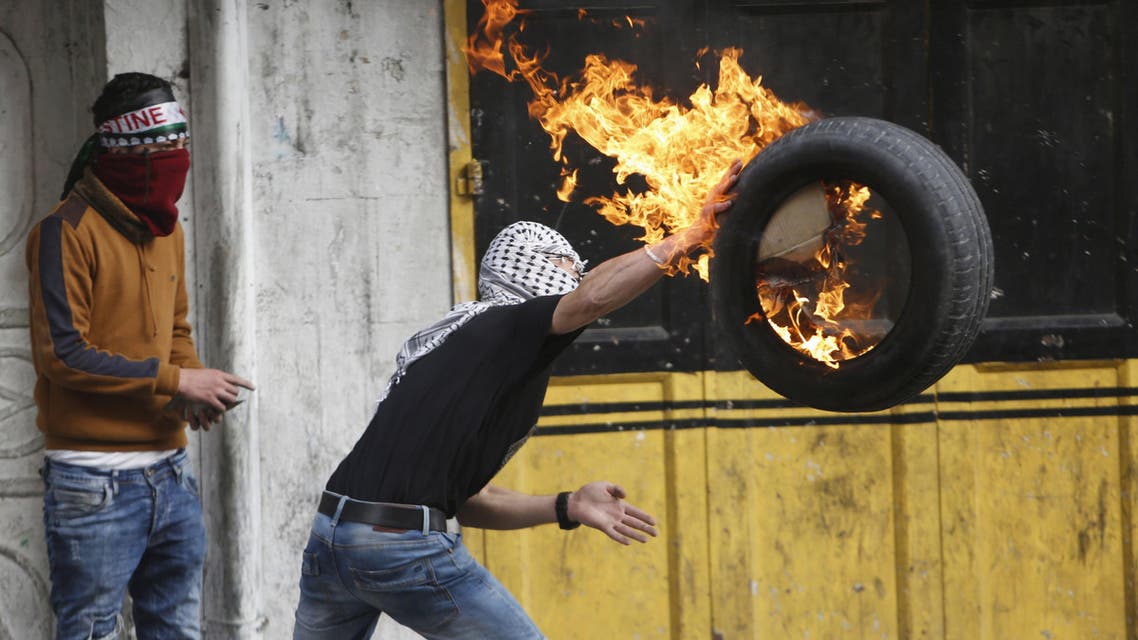 A Palestinian protester throws a burning tyre during clashes with Israeli troops following a protest demanding Israel to return the bodies of Palestinians who allegedly stabbed Israelis, in the West Bank city of Hebron Nov. 4, 2015. (Reuters) 