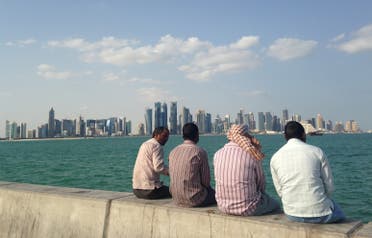  FILE - In this Nov. 7, 2014, file photo, men talk by the sea overlooking the Qatar skyline in Doha, Qatar. Amnesty International said Thursday, May 21, 2015, that Qatar is failing to deliver on reforms for its low-paid migrant workers a year after the wealthy Gulf nation announced plans to improve conditions for laborers building its highways, hotels, stadiums and skyscrapers. (AP Photo/Rob Harris, File)