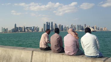  FILE - In this Nov. 7, 2014, file photo, men talk by the sea overlooking the Qatar skyline in Doha, Qatar. Amnesty International said Thursday, May 21, 2015, that Qatar is failing to deliver on reforms for its low-paid migrant workers a year after the wealthy Gulf nation announced plans to improve conditions for laborers building its highways, hotels, stadiums and skyscrapers. (AP Photo/Rob Harris, File)
