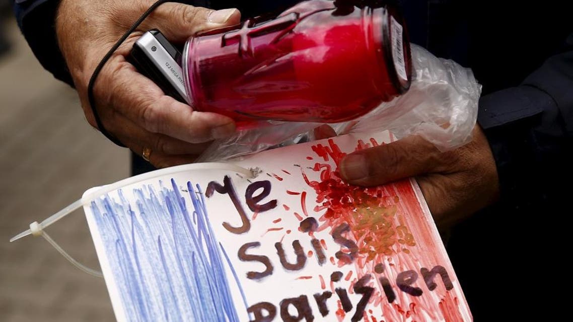 A man holds a candle and a drawing depicting the French flag and carrying the words "I am Parisian" in front of the French embassy after attacks in Paris on Friday, in Warsaw, Poland November 14, 2015. (Reuters)