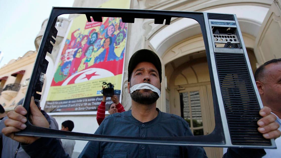 A TV journalist with his mouth taped holds up a television frame during a protest to show support for his colleagues in Tunis April 25, 2012. (Reuters)