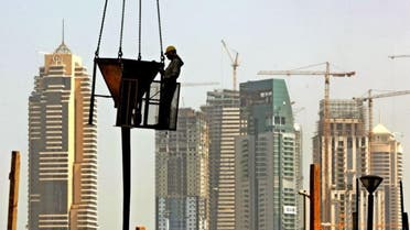 With a general view of Dubai Marina towers, a laborer holds a concrete bucket below a crane at a construction site in Dubai. (File photo: AP)