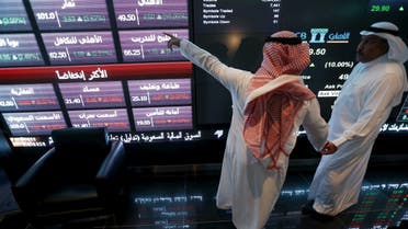 File photo of investors talking as they monitor screens displaying stock information at the Saudi Stock Exchange. (File photo: Reuters)