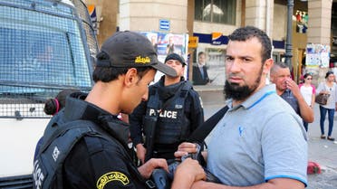  Tunisian police checks a demonstrator during a march under heavy security to protest a law offering amnesty for those accused of corruption, in Tunis, Tunisia, Saturday Sept. 12, 2015. The controversial draft law on economic reconciliation is a centerpiece of the new government's program and seeks to boost the economy by clearing cases against businessmen and civil servants accused of corruption. (AP Photo/Riadh Dridi)