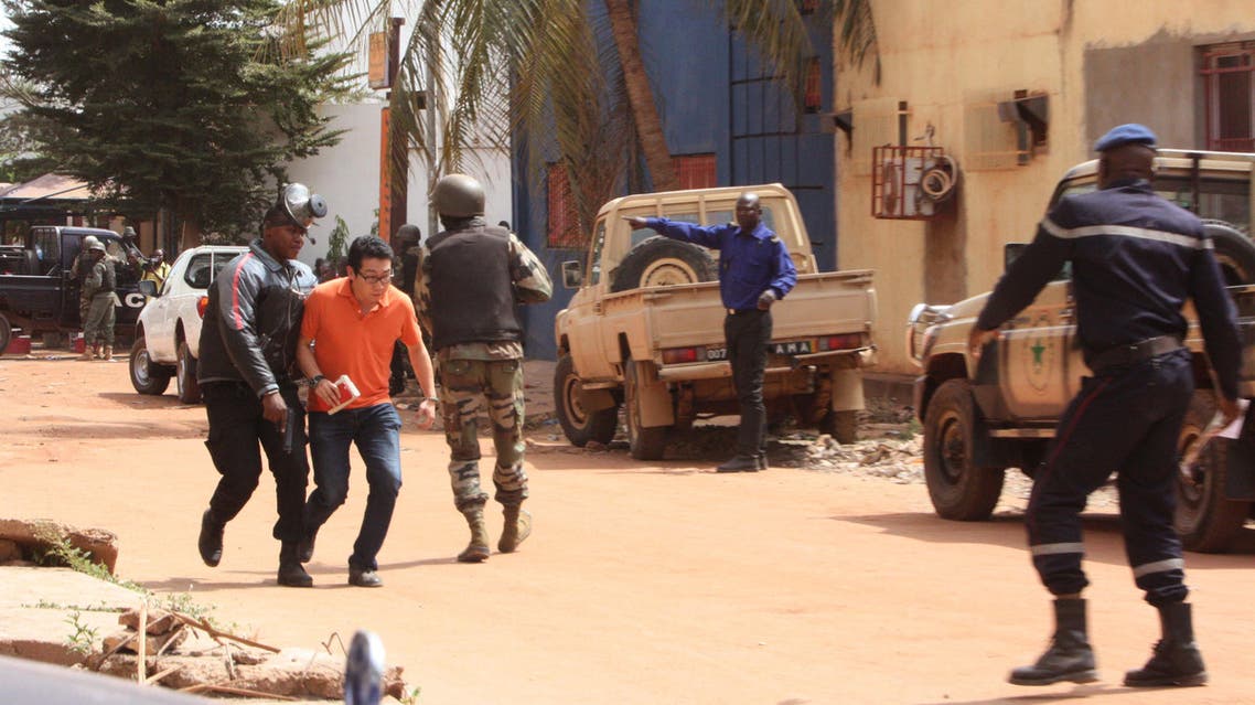 A Mali trooper, left, assist a hostage, second left, to leave the scene, from the Radisson Blu hotel to safety after gunmen attacked the hotel in Bamako, Mali, Friday, Nov. 20, 2015.
