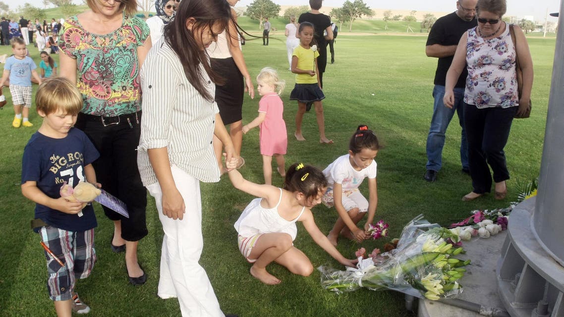 Children place flowers during a memorial held at the "Aspire Zone" close to the scene where two-year-old New Zealand triplets perished in a massive fire that tore through a nursery at a Qatar shopping mall in Doha, Tuesday, May 29, 2012.