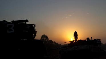 An Israeli soldier stands on top of a military vehicle as the sun rises in a staging area near the Israel Gaza Border, southern Israel (AP)