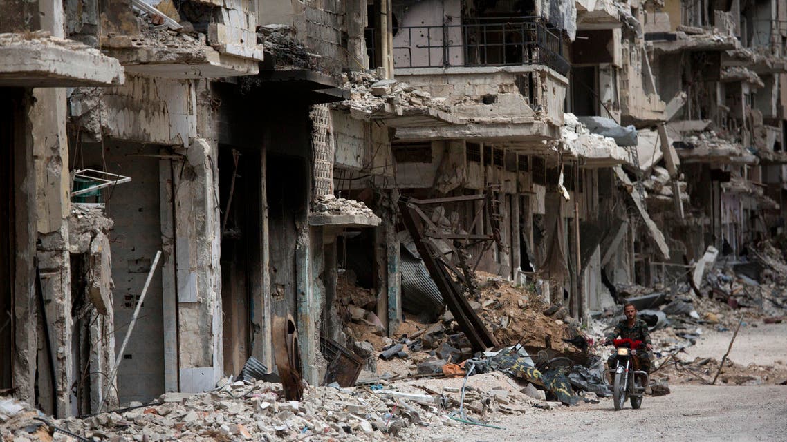 In this Thursday June 5, 2014 photo, a man rides a motorcycle in a devastated part of Homs, Syria. Syrian government forces retook the control of Homs in May 2014, after a three year battle with rebels. (AP Photo/Dusan Vranic)
