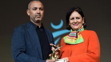 Moroccan director Mohamed Mouftakir (L) receives from Tunisian Culture Minister Latifa Lakhdar the Golden Tanit award for his film L'orchestre des aveugles" during the 26th Carthage Film Festival on November 28, 2015 in tunisian capital Tunis