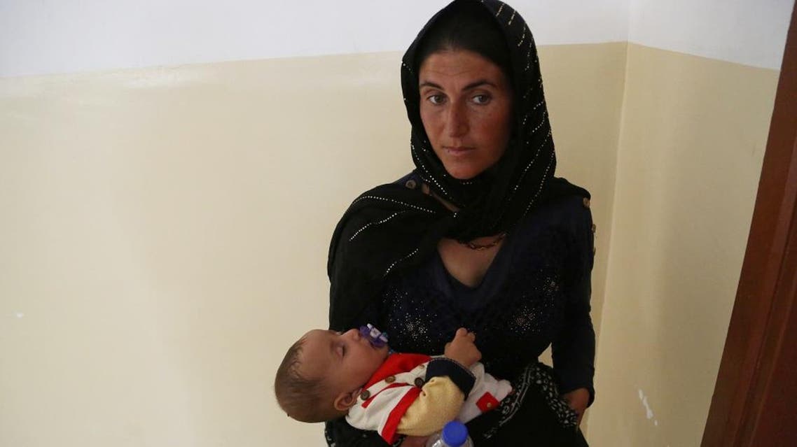 An Iraqi internally displaced Yazidi boy, held by his mother, waits for a treatment at a clinic in the town of Khanke on Sunday, Aug. 17, 2014. | AP