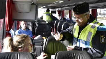 A police officer checks passports inside a bus at Lernacken, on the Swedish side of the Oresund strait, November 12, 2015. (Reuters)