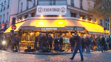People gather around La Bonne Biere cafe in Paris during its reopening Friday, Dec. 4, 2015. The cafe where five people were killed by a squad of Islamic extremist gunmen on Nov. 13, terrorizing central Paris reopened for business Friday. (AP Photo/Jacques Brinon)