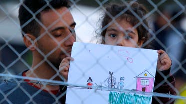 A young migrant girl holds up a drawing in a makeshift camp on the Macedonian-Greek border, near Gevgelija, Macedonia. (Reuters)