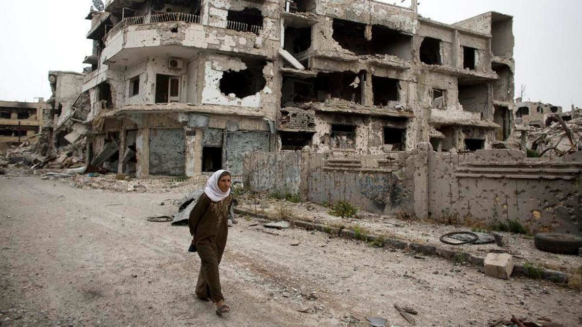 In this June 5, 2014 photo, a woman walks through a devastated part of Homs, Syria. Syrian government forces retook the control of Homs in May 2014, after a three year battle with rebels. (AP Photo/Dusan Vranic)