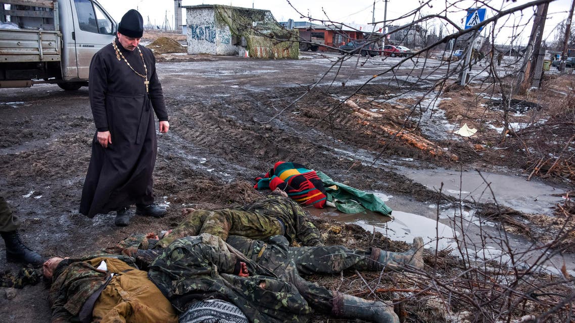 FOR USE AS DESIRED, YEAR END PHOTOS - FILE - An Orthodox priest stands next to the bodies of killed Ukrainian soldiers on a check-point captured by pro-Russian rebels at the town of Krasniy Partizan, eastern Ukraine, Saturday, Jan. 24, 2015. The fighting continues despite several cease fire declarations. (AP Photo/Mstyslav Chernov, File)