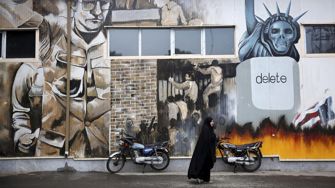 An unidentified woman walks under an anti-U.S. graffiti painted on the walls of the former U.S. Embassy in Tehran, Iran, Saturday, Nov. 2, 2013. Iran’s hardliners unveiled two new “Death to America” songs at the site of the former U.S. embassy in Tehran Saturday to keep the anti-U.S. sentiments alive. The live performance Saturday is a warm-up to the main event: A major anti-U.S. rally on Monday marking the Nov. 4 anniversary of the U.S. embassy takeover in 1979 by militant students. The event is marked every year with protests outside the compound’s brick walls. (AP Photo/Ebrahim Noroozi)