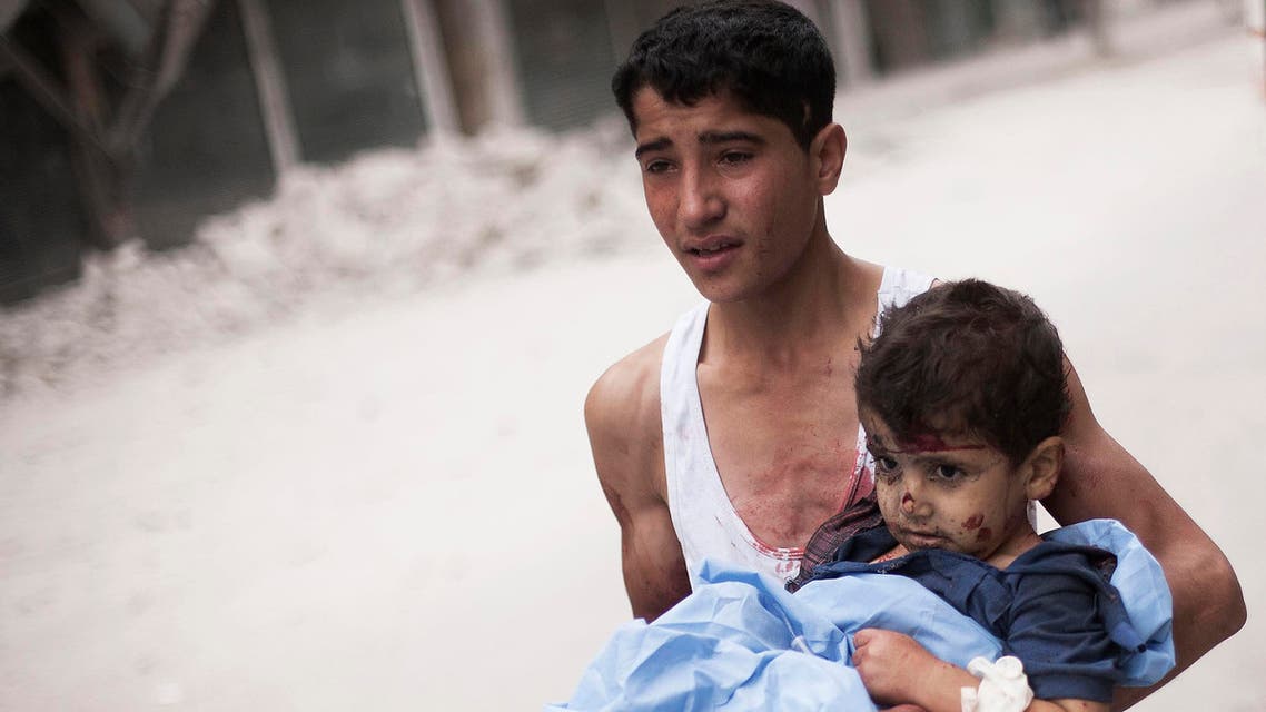 In this Thursday, Oct. 11, 2012 file photo, a Syrian youth holds a child wounded by Syrian Army shelling near Dar al-Shifa hospital in Aleppo, Syria. The Aleppo rebellion started off in the rural areas of Aleppo province, not in the city as was the case in most other parts of Syria.