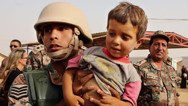 A Jordanian soldier carries a Syrian child arriving in Jordanian territory in the Roqban reception point near the northeastern Jordanian border with Syria. (File photo: AP)