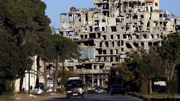 Vehicles drive in front of damaged buildings near the new clock square in the old city of Homs. (Reuters)
