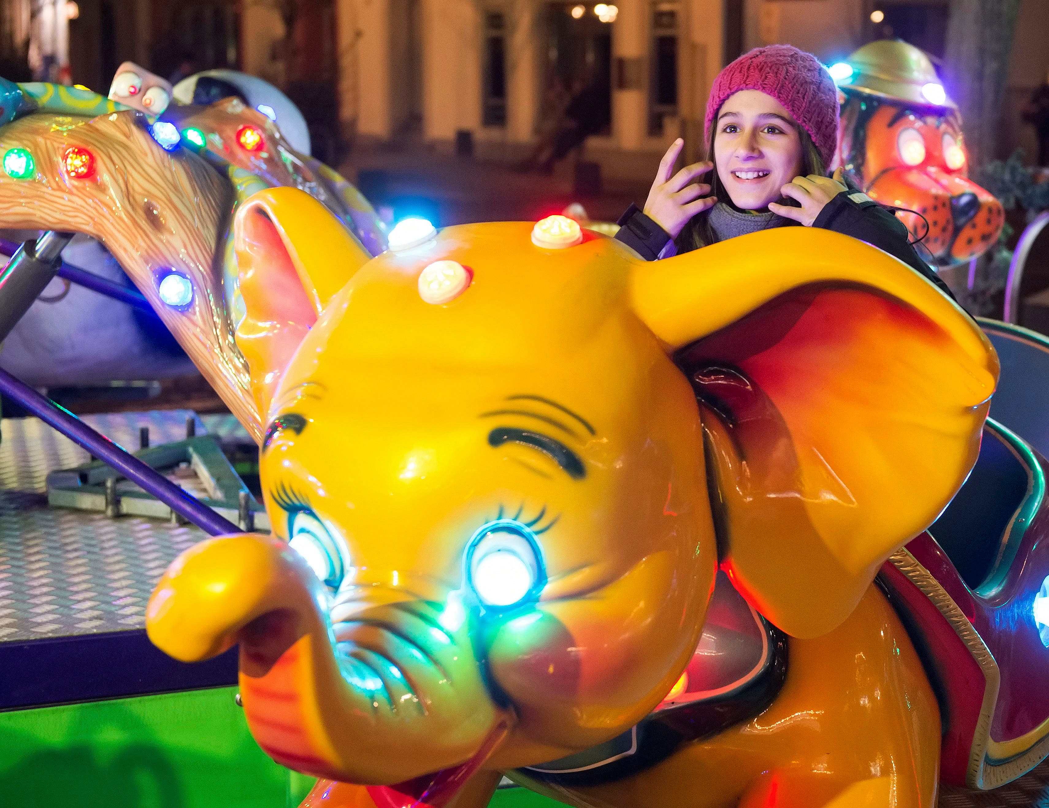 In this photo taken Tuesday, Dec. 8, 2015, Syrian refugee Raghad Habashieh rides on a carousel at the Christmas market in Zwickau, eastern Germany.